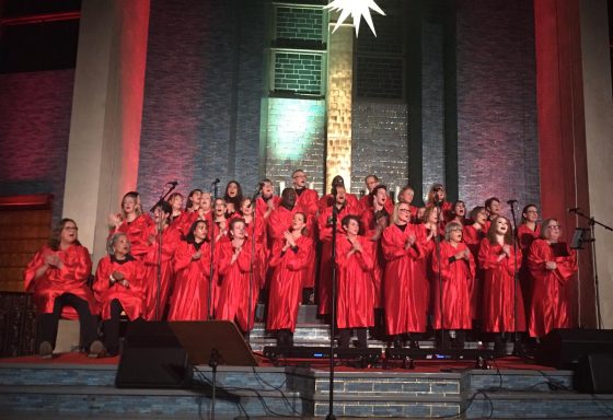 Der ONE VOICE GOSPEL CHOIR BERLIN vor dem Altar in der bunt erleuchteten Gustav-Adolf-Kirche