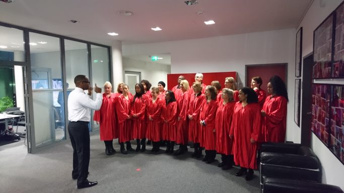 Der ONE VOICE GOSPEL CHOIR BERLIN steht im Flur und singt sich für seinen Auftritt ein