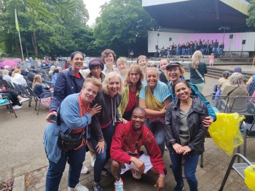Der ONE VOICE GOSPEL CHOIR hat sich auf dem Festivalgelände eingefunden und wartet auf seinen Auftritt. Alle haben Regensachen an.